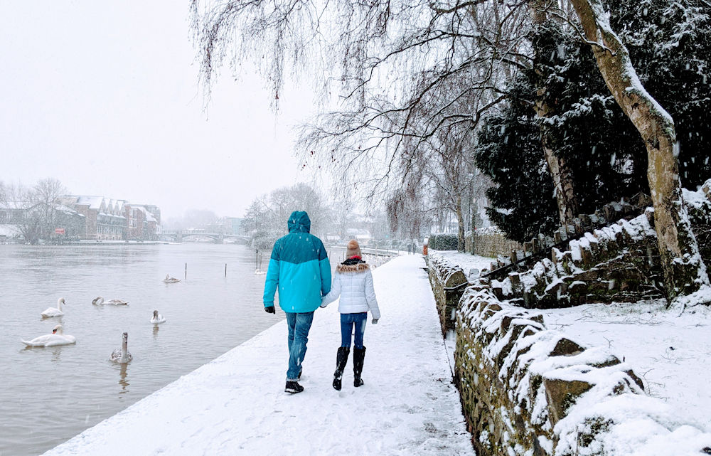 Father and daughter walk by the River Thames in the snow